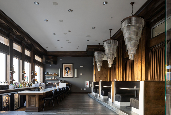 hotel bar area with large chandeliers and table seating