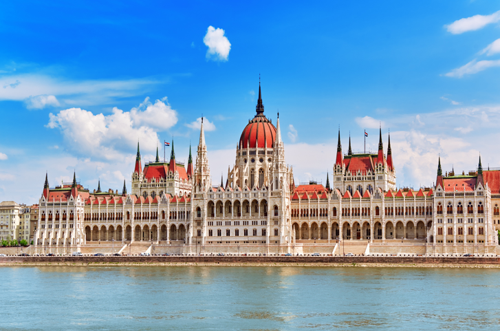A government building with a red dome by the river under blue sky.