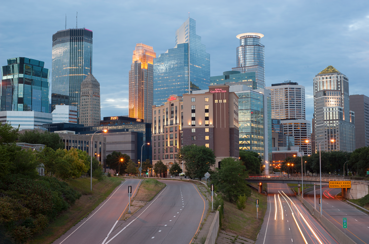 City skyline with various modern skyscrapers under a cloudy sky.