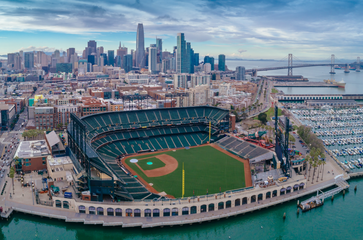 Aerial view of a baseball stadium by the water with skyscrapers in the background.