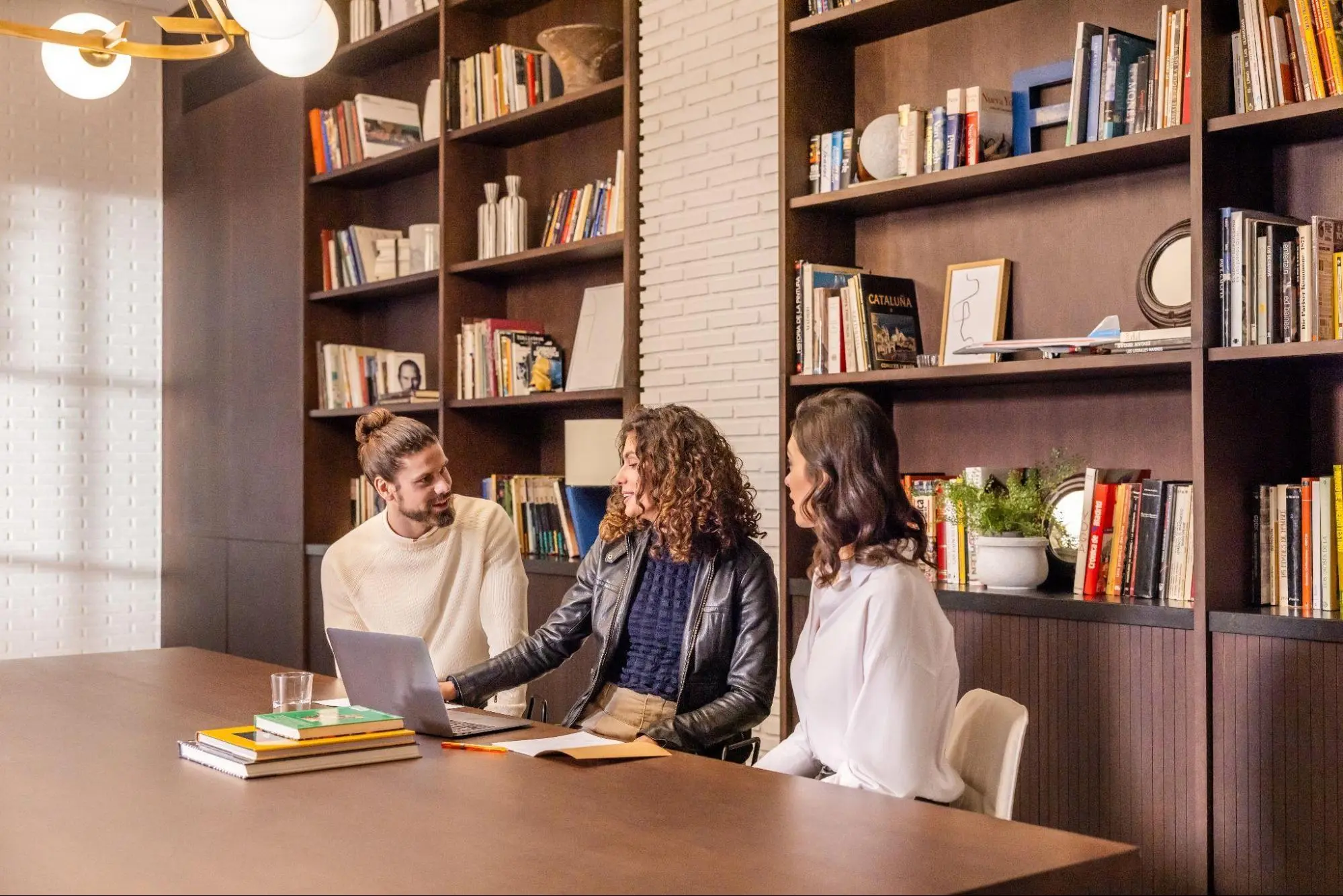 three people talking to each other by a desk